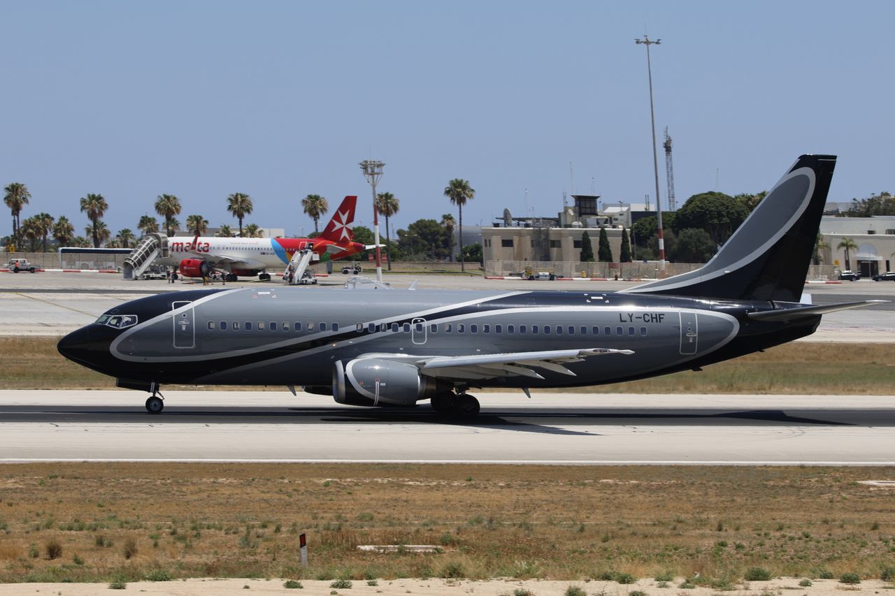 The Art of Drawing Readers In: Your attractive post title goes here A sleek black airplane taxis on the runway at a sunny airport with palm trees and terminal buildings in the background.