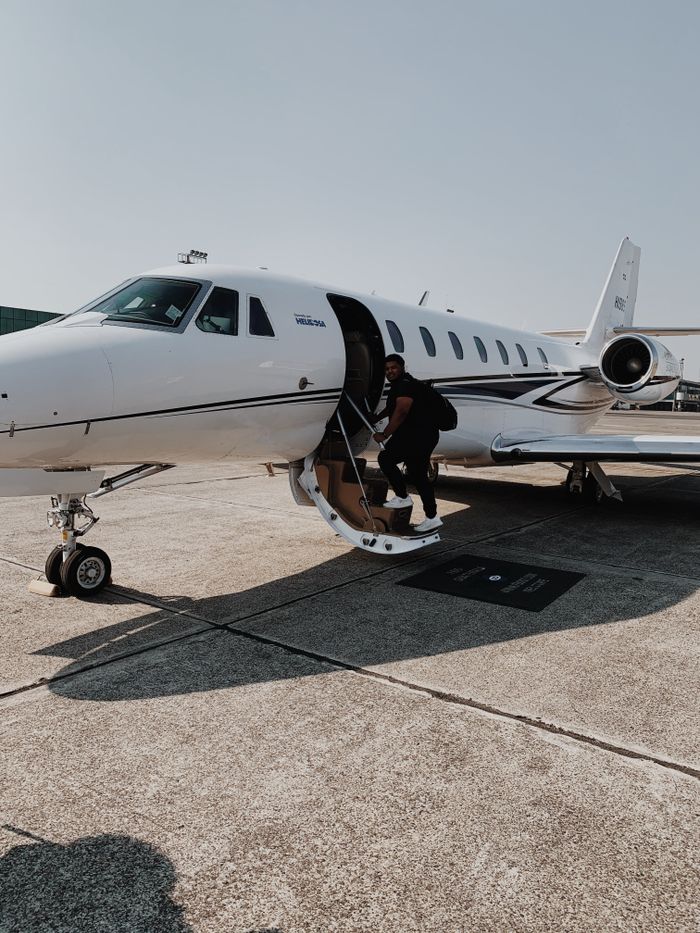 Services A passenger boards a private jet at a sunlit airport runway, capturing luxury travel.
