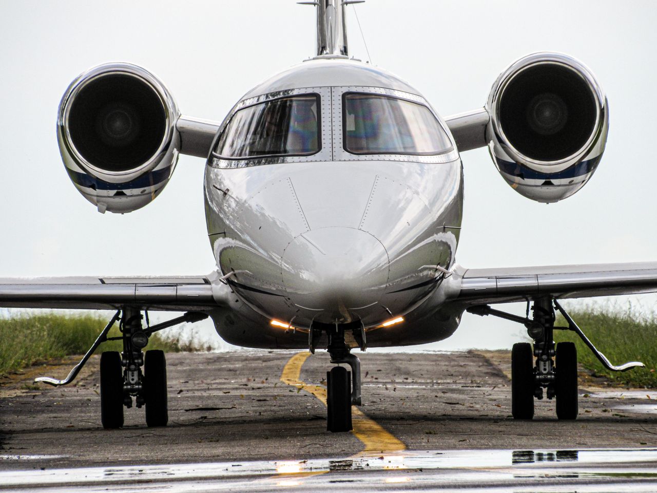 About Front view of a sleek jet aircraft on a runway, ready for takeoff in daylight.